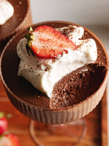 A chocolate mousse cup with a spoonful scooped out of the cup to show the texture inside.