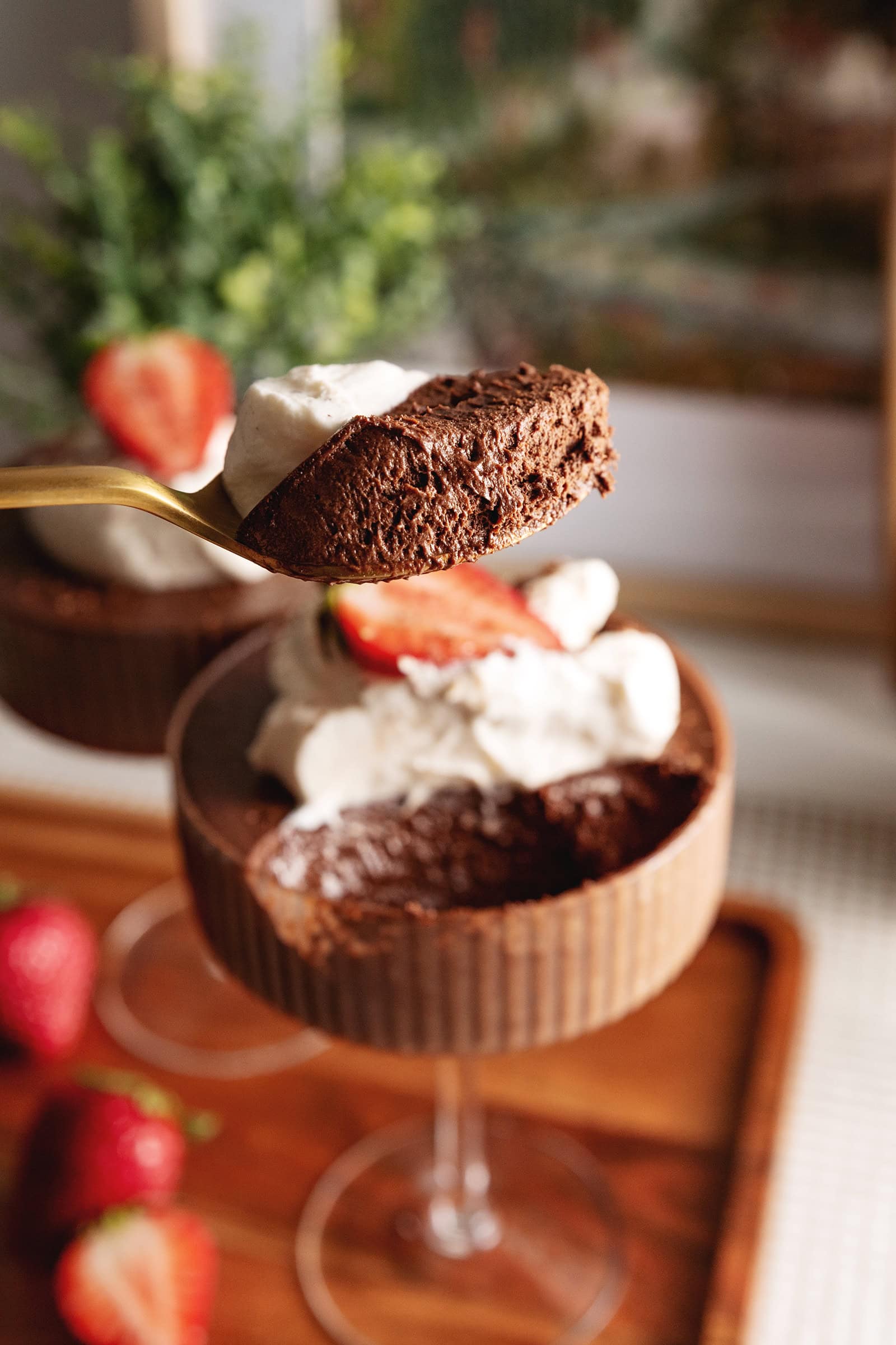 A spoonful of chocolate mousse held above the rest of the glass.