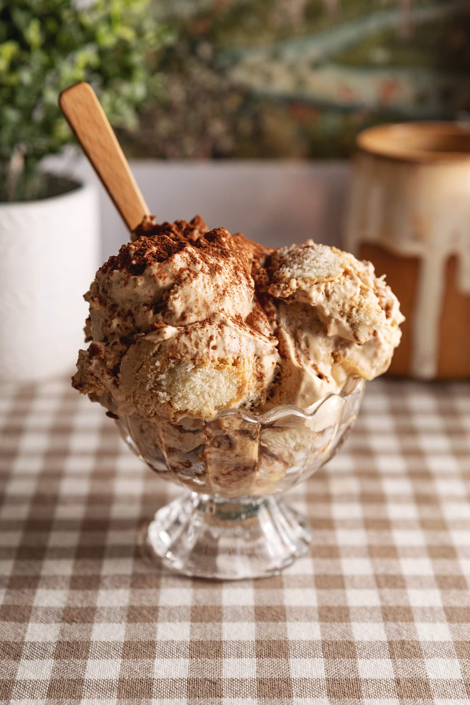 Several scoops of tiramisu ice cream in a glass bowl with a wooden spoon sticking out.
