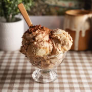 Several scoops of tiramisu ice cream in a glass bowl with a wooden spoon sticking out.
